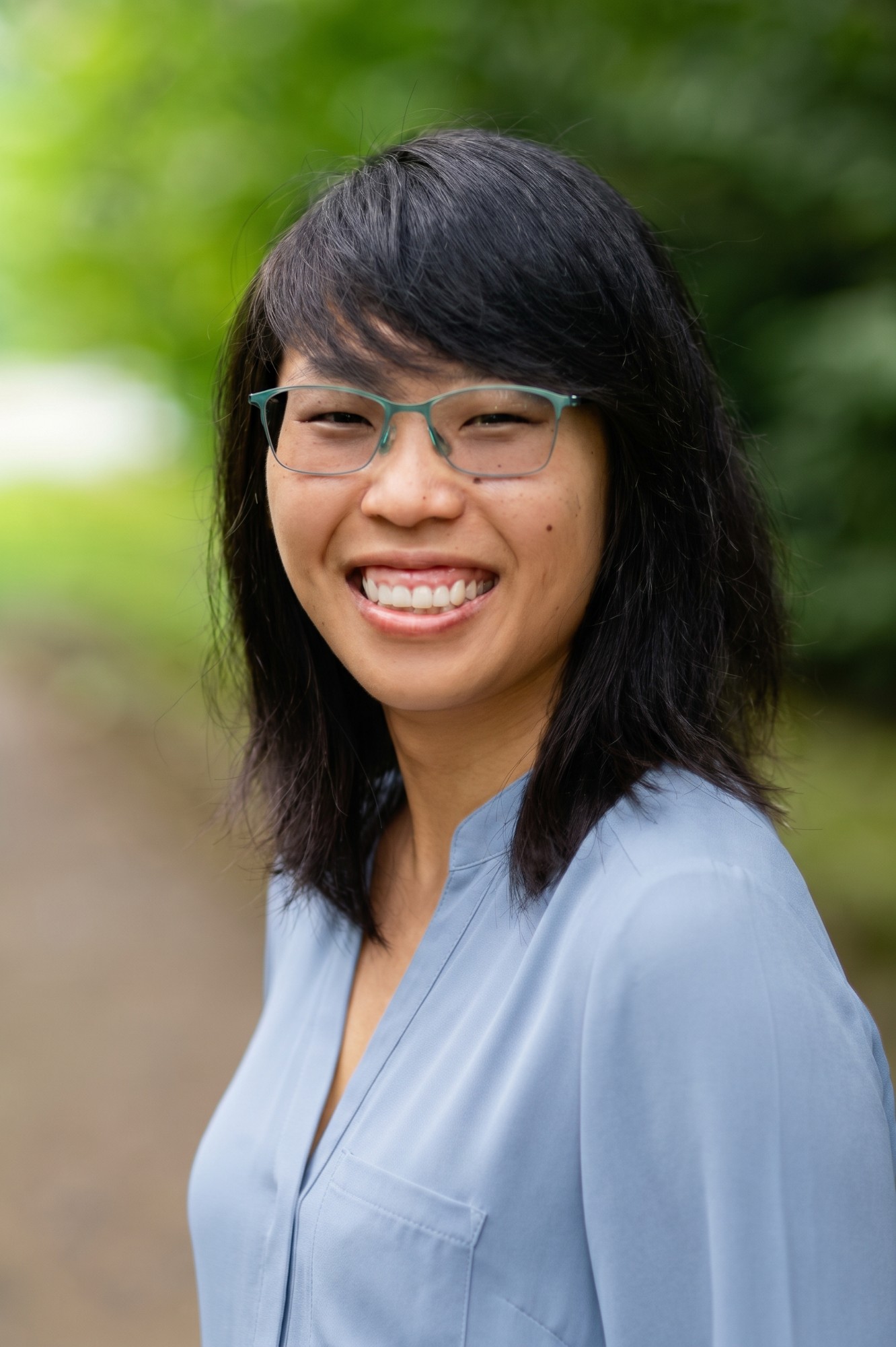 Julie smiling outdoors, wearing a blue blouse